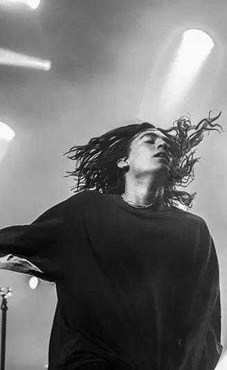 長髪の男性ボーカリストが、髪をなびかせて躍動する様子。