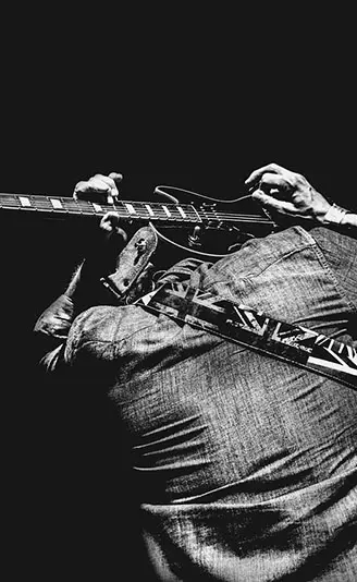 ギターを頭上で引いている男性を後ろから見た様子。